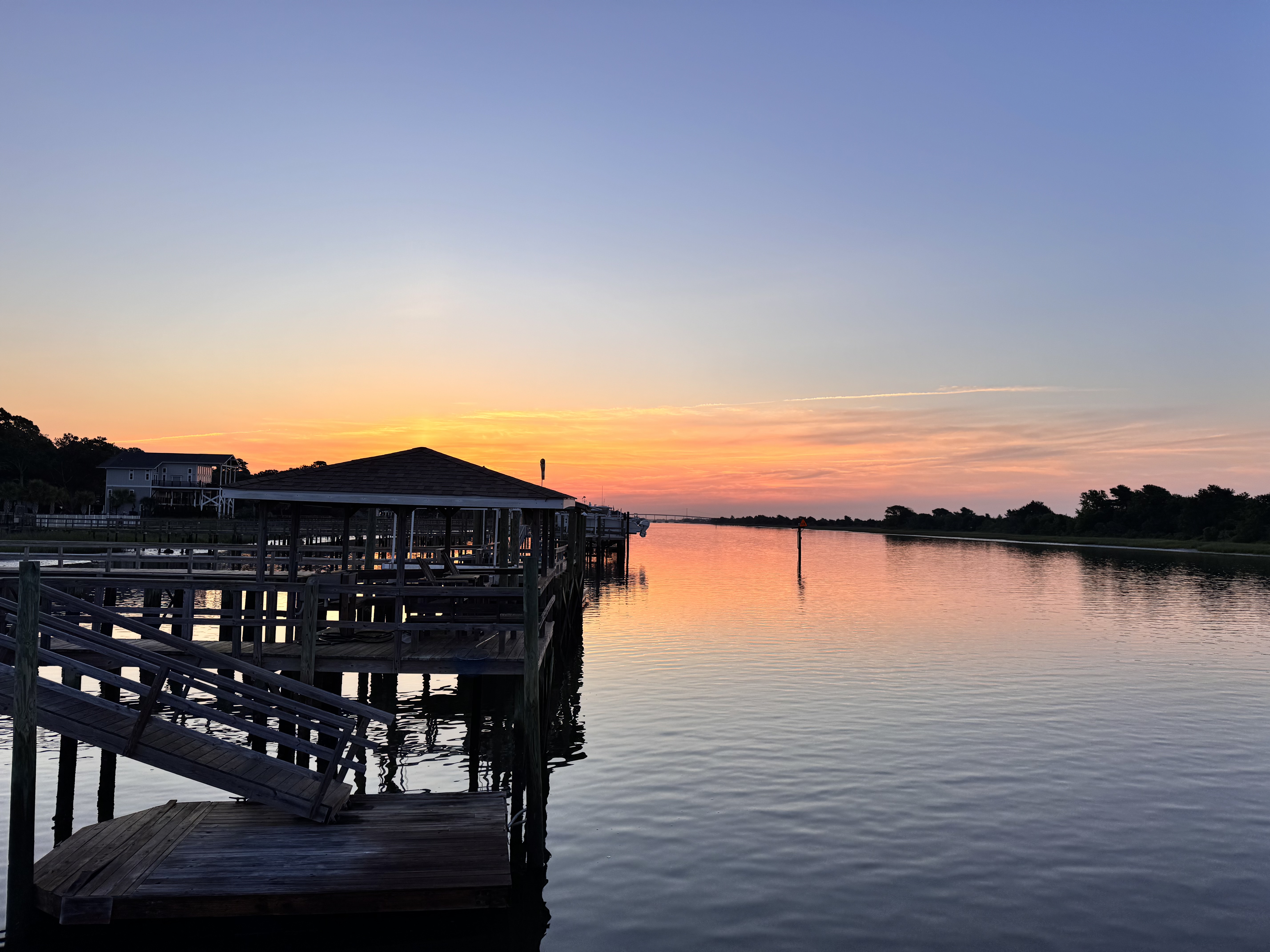 Waterfront dock at sunrise with pink and orange sky